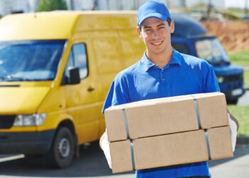 Smiling young male postal delivery courier man in front of cargo van delivering package